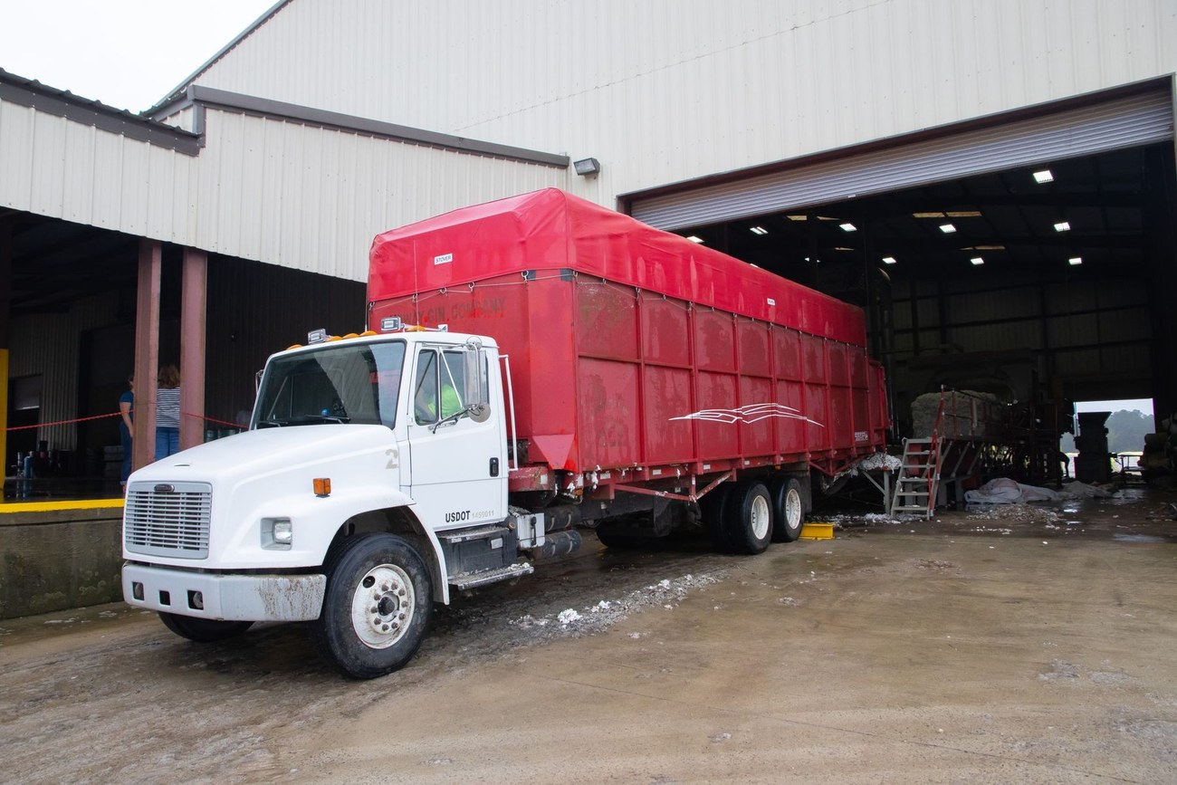 Cargo truck with a red trailer beside a warehouse loading entrance